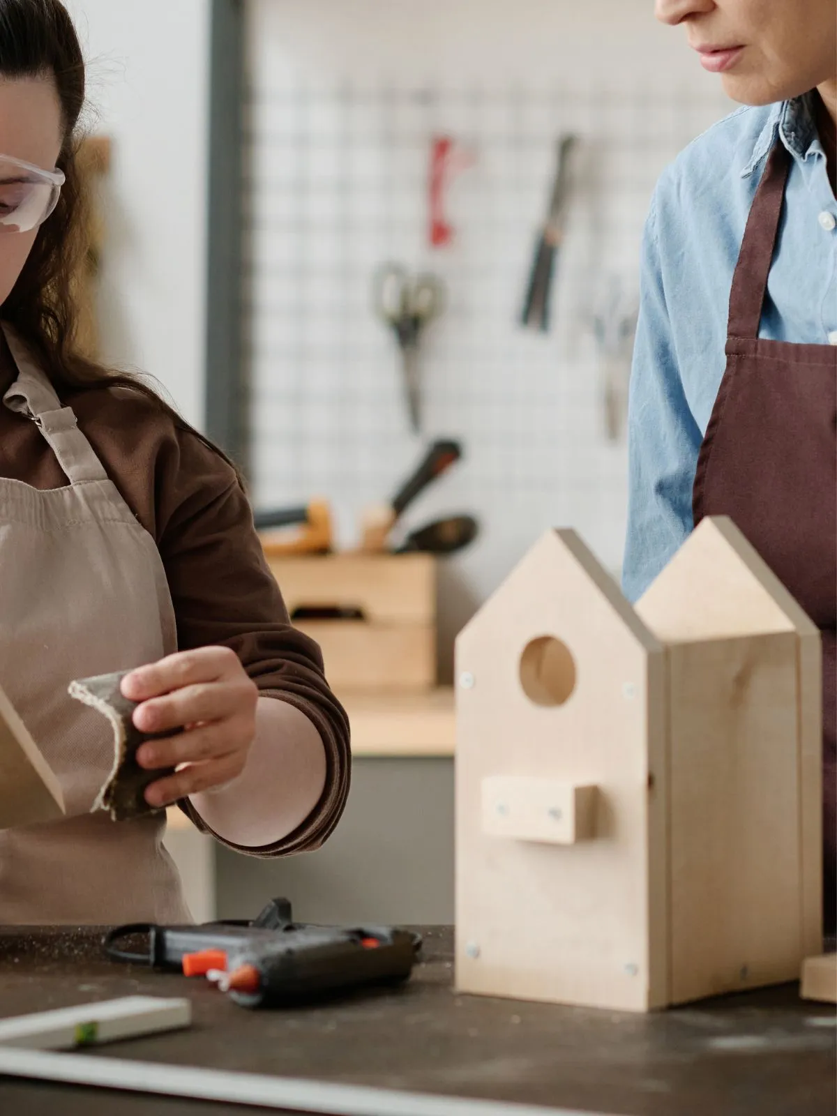 Ce sont deux personnes en train de fabriquer un nichoir à oiseaux