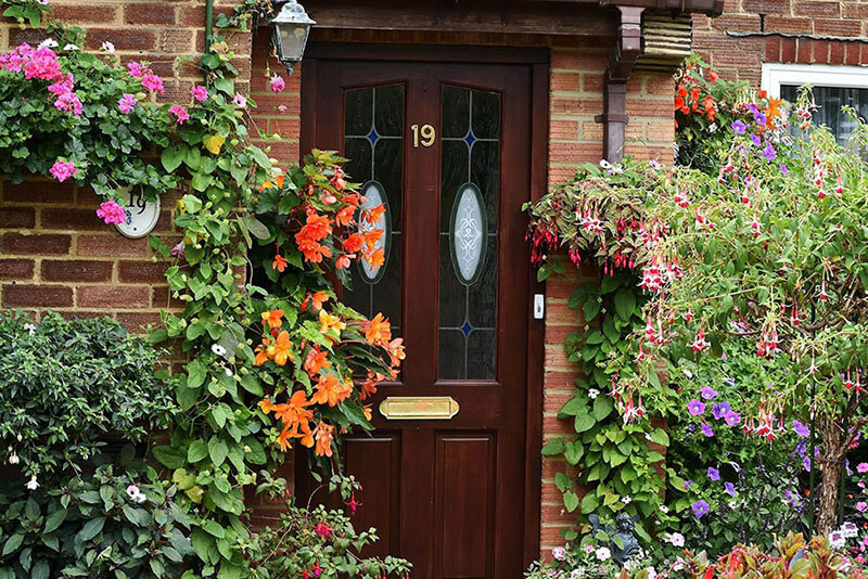 Front of an English house with a very flowery and colourful garden